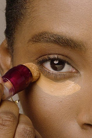 Woman applying easy eraser under her eyes